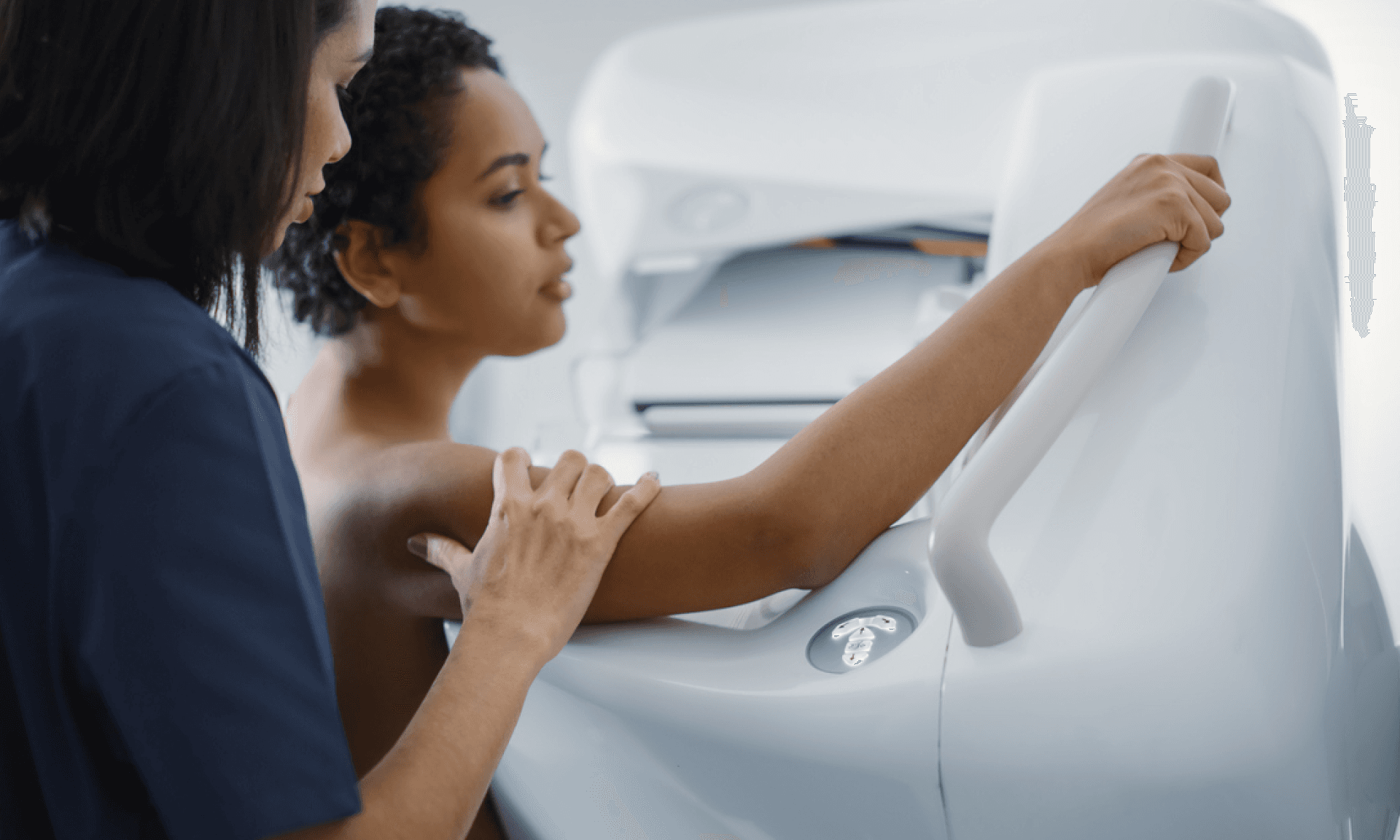 A woman getting a mammogram with a medical provider standing behind her