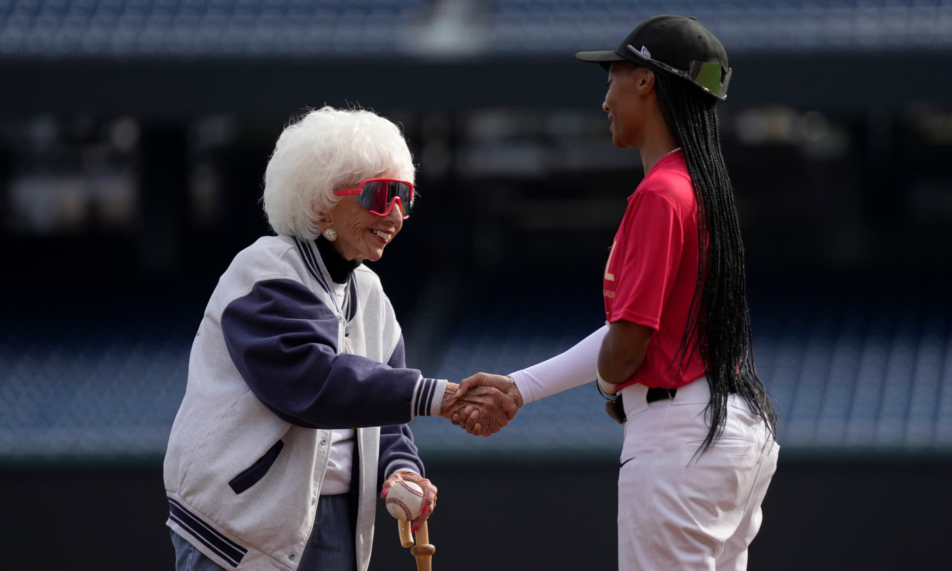 Maybelle Blair, who played in the All-American Girls Professional Baseball League, shakes hands with Mo'ne Davis after throwing a ceremonial first pitch ahead of a scrimmage in tryouts for the Women’s Professional Baseball League at Nationals Park